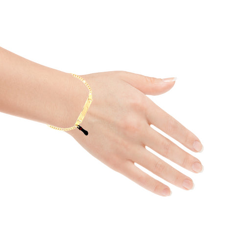 A hand adorns a Kids Bracelet Black Figa Hand Charm and Plate with Figaro link, crafted in 14k gold-filled material and featuring a sleek design enhanced by a black figa hand charm, offering an added layer of sophistication.